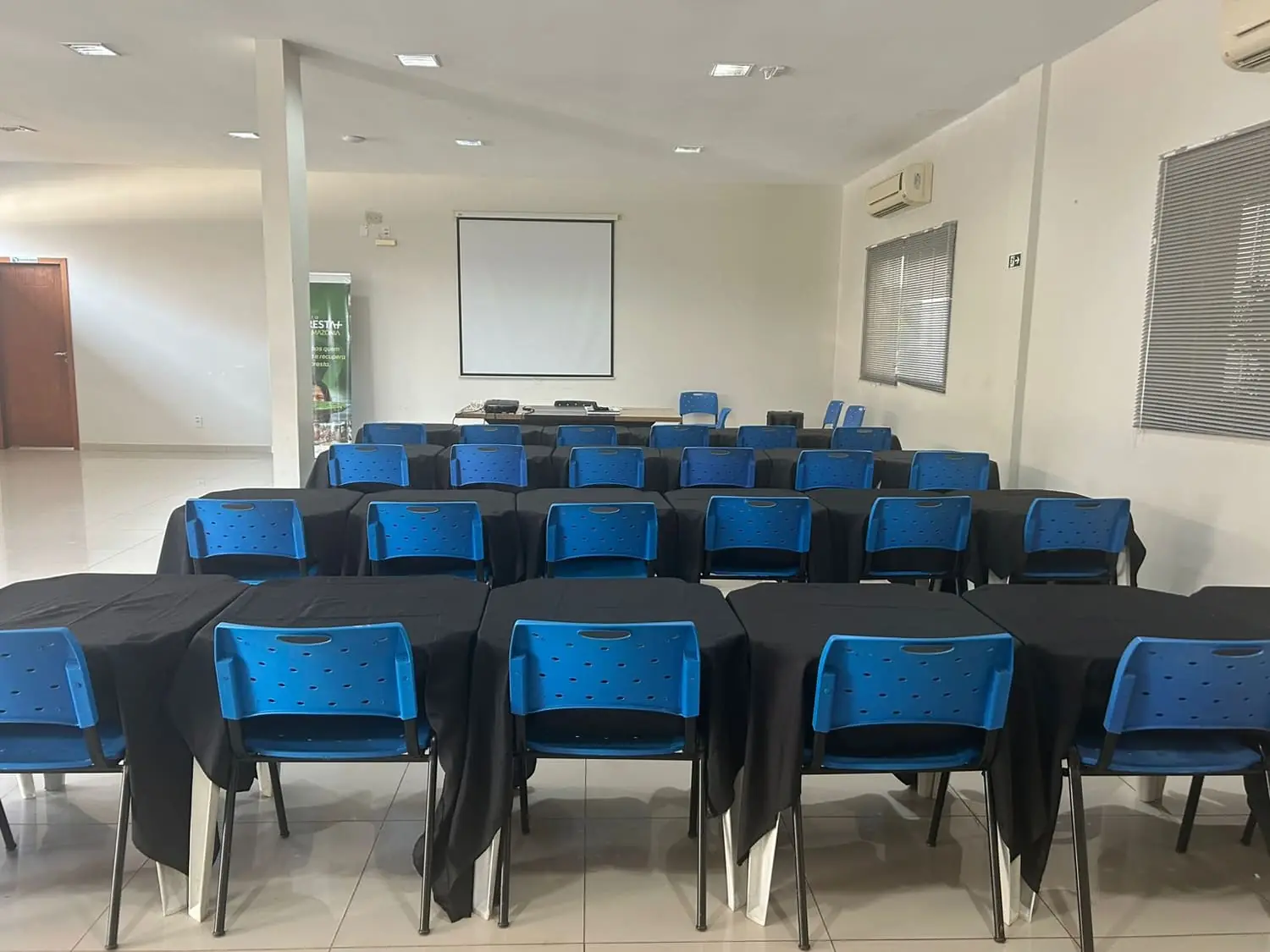 Auditório montado em formato treinamento, com mesas em fileiras