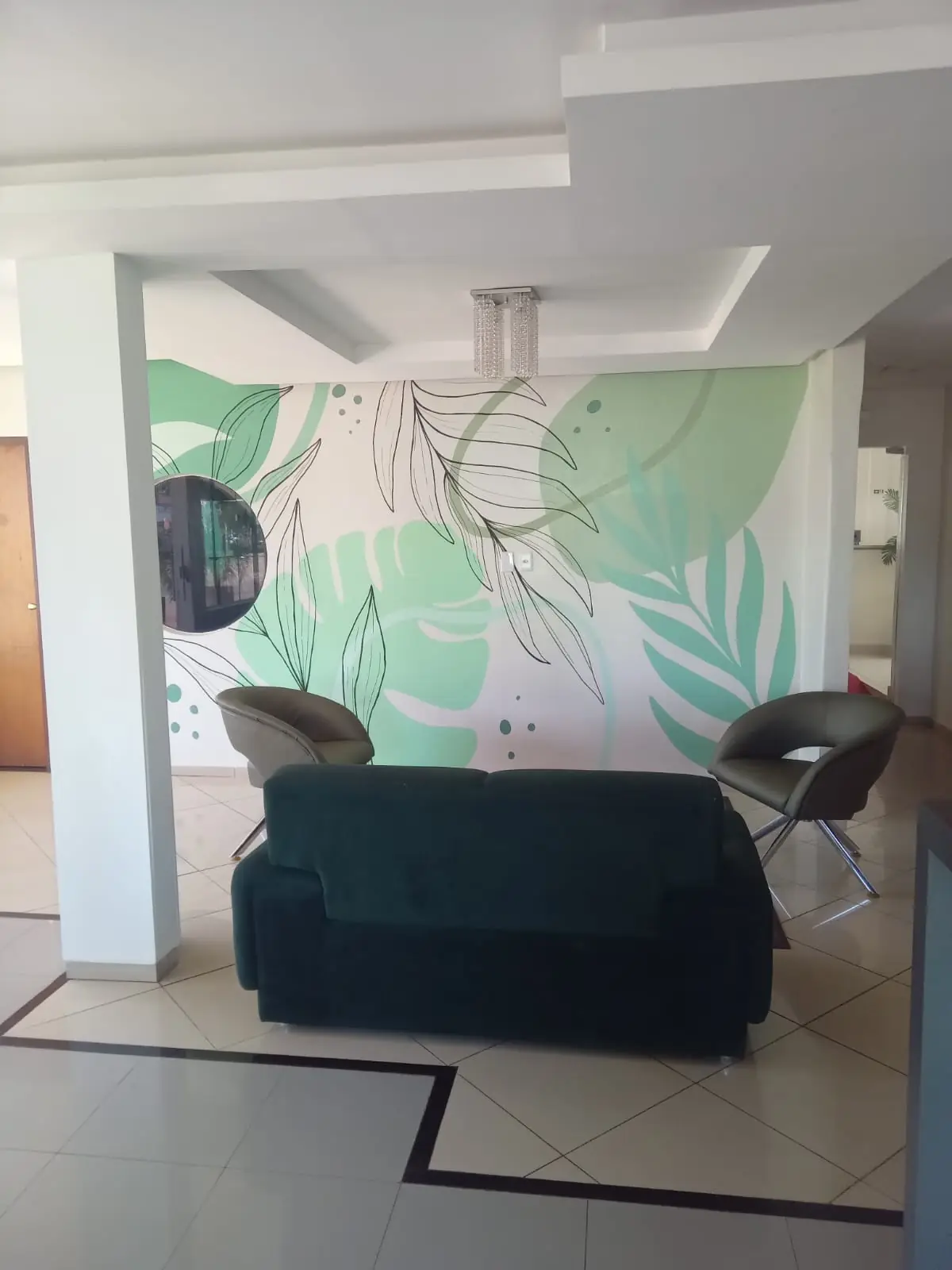 Hall com sofá e mural de folhagens
