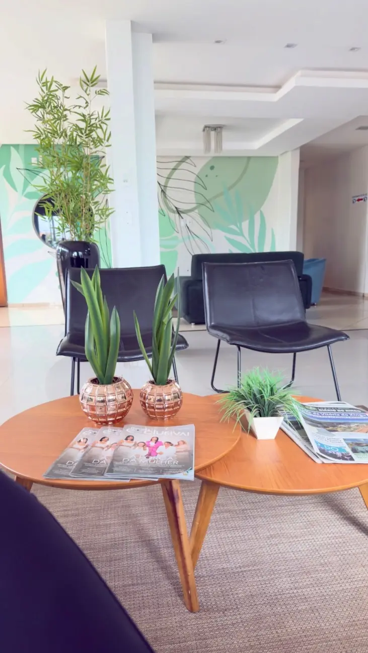 Área de convivência com mesas de apoio e plantas